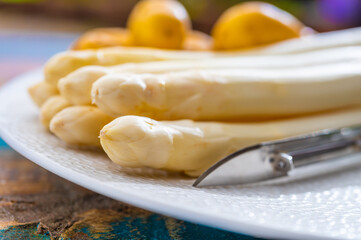 Ingredients for spring vegetarian dinner, high quality Dutch white asparagus, washed and peeled on board, ready to cookand and young potatoes