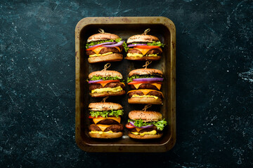 Delicious grilled homemade burgers. Burger menu. Top view. On a black stone background.