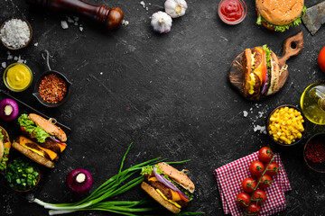Set of burgers with beef, tomatoes, cheese, onions and salad. Street food. Top view. On a black stone background.