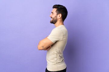 Young handsome man with beard over isolated background in lateral position