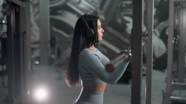 Close-up of a sexy girl in headphones working out in the gym