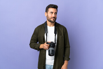 Photographer man over isolated purple background having doubts while looking side