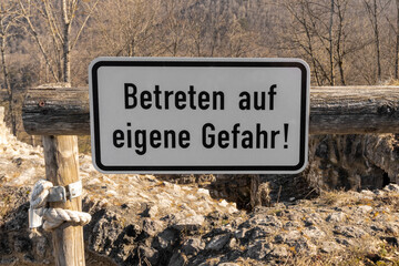 nameplate "Betreten auf eigene Gefahr!" with an inscription next to the historical ruins