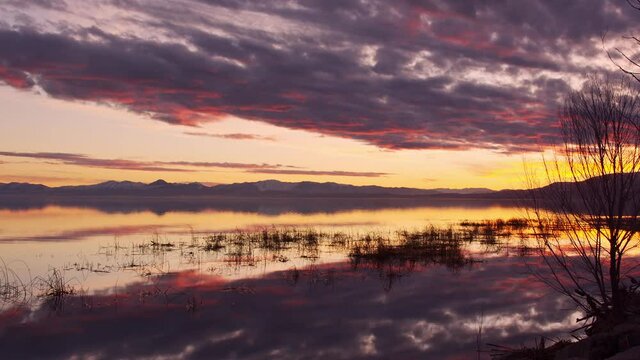 Colorful sunset reflecting in water over Utah Lake moving in slow motion as the water slowly ripples.
