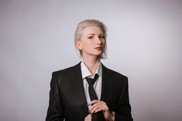 Fashionable portrait of a woman dressed in men's clothing. Girl in a white shirt, jacket and tie on...