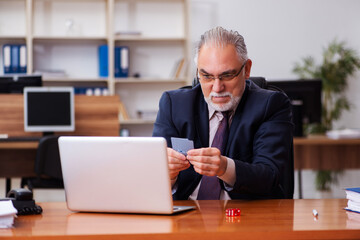 Old male employee playing cards at workplace