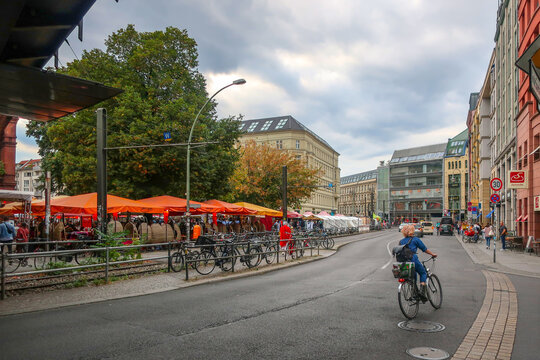 A woman rides a bicycles down a busy street past the Hackescher Markt square in the Mitte district of Berlin Germany