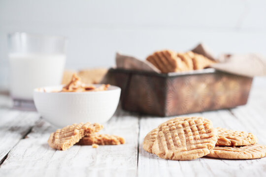 Fresh baked, homemade peanut butter cookies and milk over a white rustic table. Selective focus with blurred background.