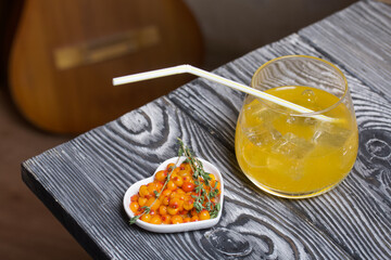 Cocktail with sparkling wine and sea buckthorn. Sea buckthorn bellini with ice. Decorated with thyme sprigs.