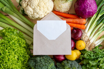 White paper and letter envelope inside on assorted organic vegetables for healthy eating.