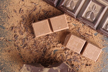 International Chocolate Day flatlay kind of top pieces of milky dark chocolate bar and cocoa pistons on a grey black background with place for text and copyspace