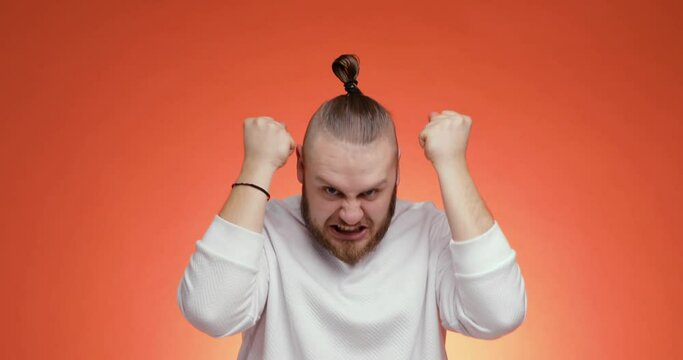 Sad mad crazy displeased young bearded man in sweater screaming isolated on red background. People negative emotions lifestyle concept. Angry yelling tired exhausted man looking at camera.