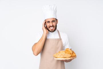 Male baker holding a table with several breads isolated on white background unhappy and frustrated with something. Negative facial expression