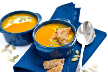 Pumpkin soup with croutons and pumpkin seeds on white background