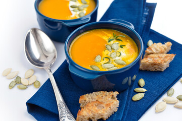 Pumpkin soup with croutons and pumpkin seeds on white background