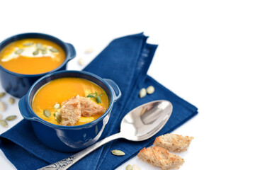 Pumpkin soup with croutons and pumpkin seeds on white background. Space for your text