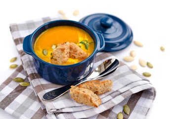 Pumpkin soup with croutons and pumpkin seeds on white background