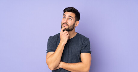 Caucasian handsome man having doubts over isolated purple background
