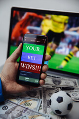 Lucky winner at football betting with phone in hand and dollar bills. Betting concept. Vertical image.