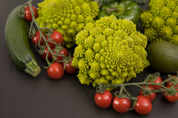 fresh vegetable, romanesco broccoli, pepper, zucchini and avocado, free space in your text, on a black table