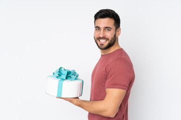 Pastry chef with a big cake isolated on white background smiling a lot