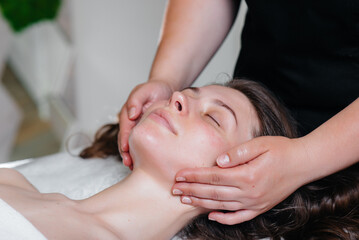 Fototapeta na wymiar A young pretty girl is enjoying a professional head massage at the Spa. Body care. Beauty salon