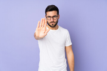 Caucasian handsome man over isolated background making stop gesture - obrazy, fototapety, plakaty
