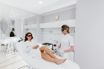 A beautiful young girl will undergo laser hair removal with modern equipment in a Spa salon. Beauty salon. Body care