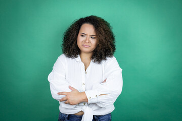 Young african american girl wearing white shirt over green background thinking looking tired and bored with crossed arms