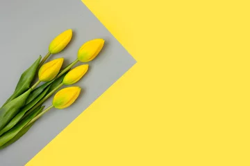 Gelbe Tulpen auf grauem Hintergrund. Trendfarbe des Jahres 2021. Leuchtendes Gelb und ultimatives Grau. Platz kopieren. Kreatives minimales Blumenkonzept. © Lyubov