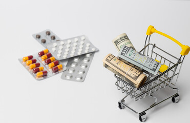 Dollar bills rolled into a tube in a cart on a white background with pills. Copy space. Medicine money saving concept.