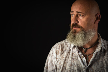 close up photo, portrait of a serious, thoughtful, bearded man on a dark background looking confidently and dramatically to the side. Concept male portrait. Low key