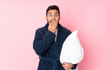 Young man going to sleep isolated on pink background with surprise facial expression