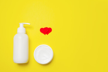 Cream in a bottle and jar with hearts on a yellow background.