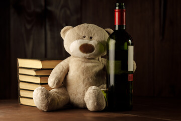 Alcohol and child abuse. Teddy bear as a symbol of child's safety and bottle close-up. © burdun