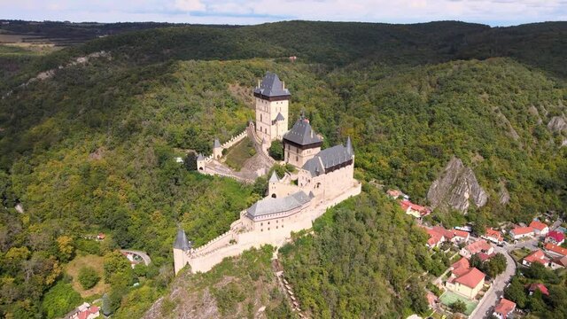 Aerial view on royal castle Karlstejn medieval, state owned castle near Prague in spring nature, lit by evening sun. Romantic Czech castle on the hilltop. Central Bohemia, czech landscape, Czechia