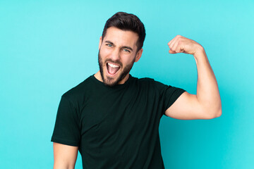 Caucasian handsome man isolated on blue background doing strong gesture