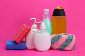 sponges, bottled detergents, rags on a pink background, home cleaning concept