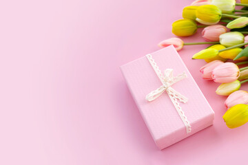 Bouquet of colorful tulips and gift box isolated on pink background. Spring flowers. Greeting card for Birthday, Woman, Mother's Day, Valentine's day. Flat lay. Copy space.