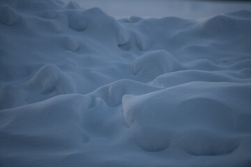 snow landscape made from mounds of snow and snow drifts sunlight causing shadows and shapes that look like faces in the freshly fallen snow on a cold winters day background for horizontal format