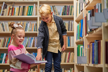school kids preparing for lesson in school library, reading textbooks together and discussing,...