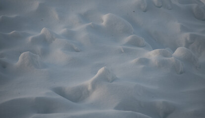 snow landscape made from mounds of snow and snow drifts sunlight causing shadows and shapes that look like faces in the freshly fallen snow on a cold winters day background for horizontal format