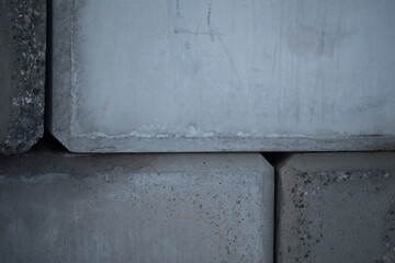 concrete cement wall of large cement blocks stacked up as exterior wall of building on construction site weathered hard surface in shades of grey stacked together horizontal format