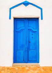 Fototapeta premium House with a beautiful blue wooden door, Mediterranean style, and an aged white facade.