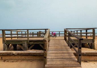 Fototapeta premium Wooden platform with some bicycles, on a beach with cloudy skies on a cold winter day.