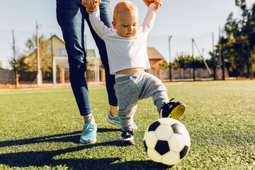 young mom with son play soccer on the field, outdoors