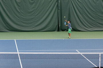 Little Boy Playing Tennis on an Indoor Tennis Court