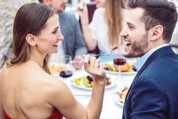 Woman feeding her man with Italian dishes in fancy restaurant
