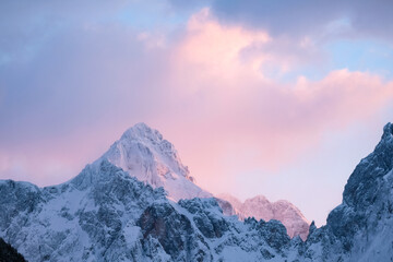 Beautiful close up shot of a pink glowing Mountain top in the Alps at sunset while wind is blowing...