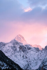 Beautiful close up shot of a pink glowing Mountain top in the Alps at sunset while wind is blowing...